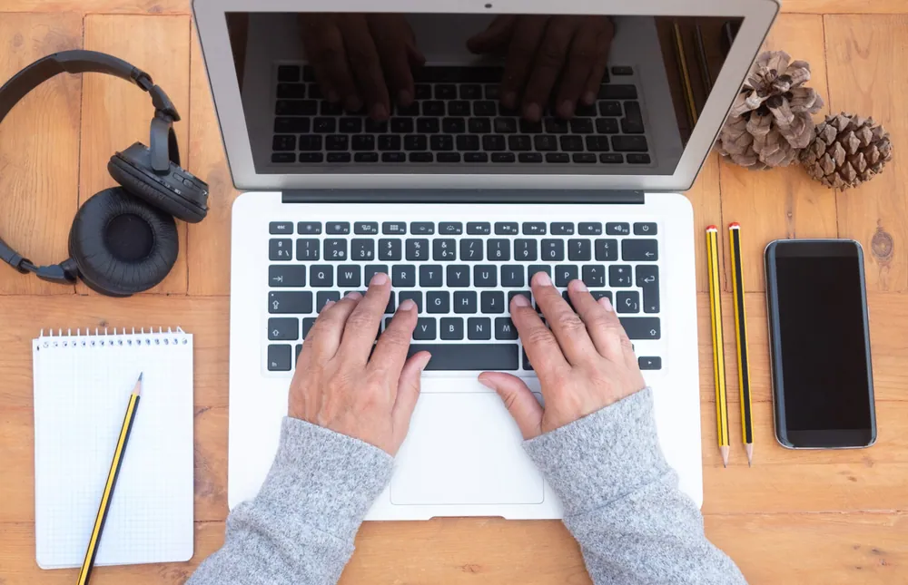 A writer’s hands at a laptop, seen from above